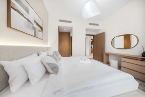 A modern hotel room with a large bed, a bedside table, a mirror, and a ceiling light. - StayShort - Peaceful 1-Bedroom, in Dubai Creek Harbour - Sleeps 4 (Dubai Creek Harbour)