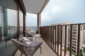 A balcony with wicker furniture, a small table, and a view of surrounding buildings. - StayShort - Peaceful 1-Bedroom, in Dubai Creek Harbour - Sleeps 4 (Dubai Creek Harbour)