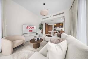 A modern living room with a sofa, a coffee table, and a dining area in the background. - StayShort - Peaceful 1-Bedroom, in Dubai Creek Harbour - Sleeps 4 (Dubai Creek Harbour)