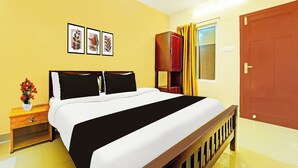 Ein Hotelzimmer mit einem Bett, einem Nachttisch, einer Blumenvase und einer Tür.