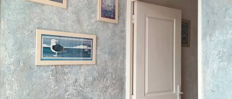 A room with a textured wall, a white door, and a small table with a red object on it.