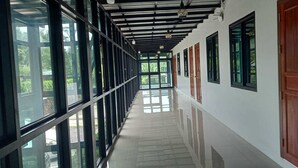 A corridor with a reflective floor, large windows, and doors with wooden panels. - Lilly Home (Khaem Son)