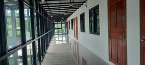 Un pasillo con suelo reflectante, ventanas amplias y puertas de paneles de madera.