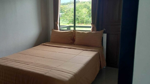A single bed with a brown bedspread in a room with a window.