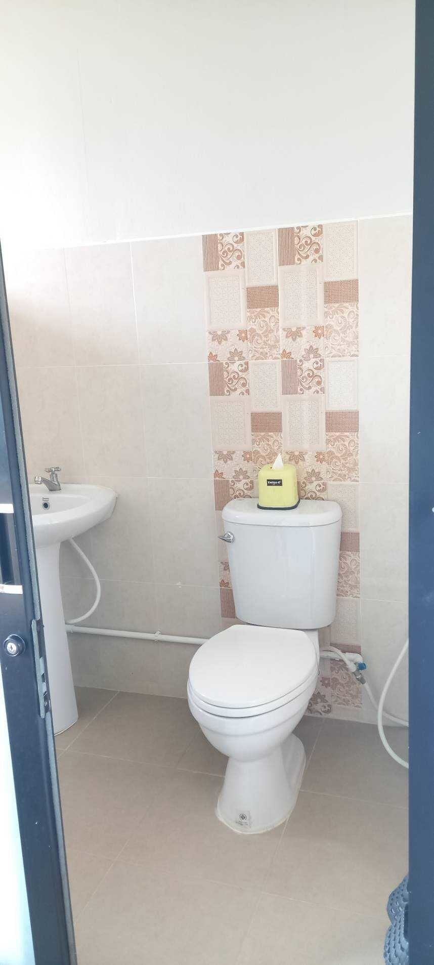 Une petite salle de bain avec des toilettes, un lavabo et des carreaux décoratifs sur les murs.
