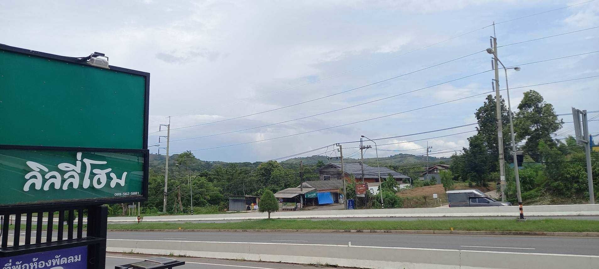 Una carretera con un cartel verde y un pequeño edificio al fondo.