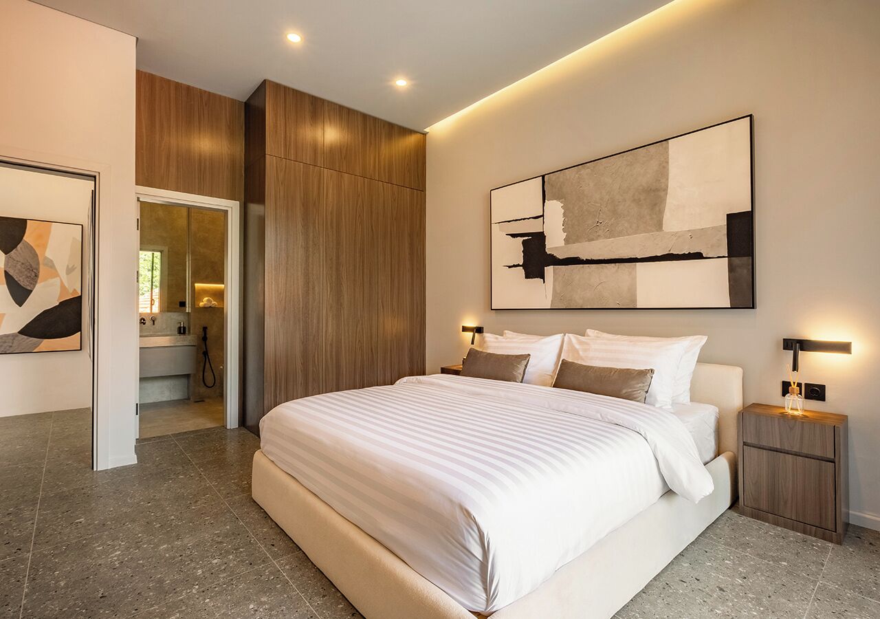 A modern bedroom with a large bed, a wooden panel wall, and a minimalist artwork above the bed.