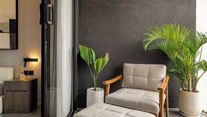 A modern living room with a sofa, a side table, and two potted plants. - Peaceful 2BR Umalas Villa Near Seminyak (Badung)