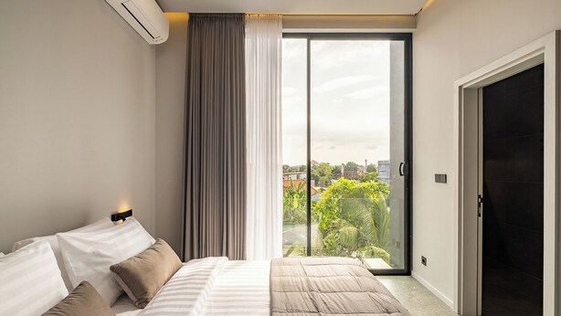 A bedroom with a bed, a sliding glass door to a balcony, and an air conditioning unit. - Peaceful 2BR Umalas Villa Near Seminyak (Badung)