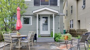 A patio with a table and chairs, a potted plant, and a door with a small porch. - Walk to Main St Stroudsburg! Historic Dtwn Home (Stroudsburg)