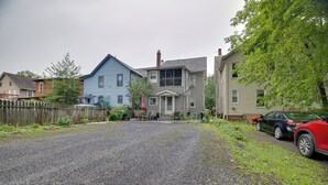 A residential street with houses, a gravel driveway, and a parked car. - Walk to Main St Stroudsburg! Historic Dtwn Home (Stroudsburg)
