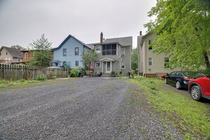 A residential street with houses, a gravel driveway, and a parked car. - Walk to Main St Stroudsburg! Historic Dtwn Home (Stroudsburg)