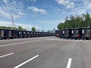 Un estacionamiento con filas de vagones de tren negros, líneas blancas de aparcamiento y un cielo despejado.