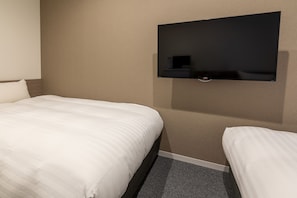 A hotel room with a bed, a small bedside table, and a wall-mounted television.