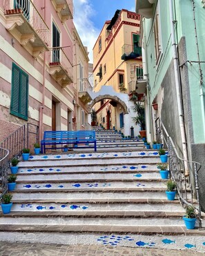 A staircase with blue fish patterns leading to a building with balconies. - Maison Tabarka: Comfort and Design Suites in the Historic Center of Carloforte (Carloforte)