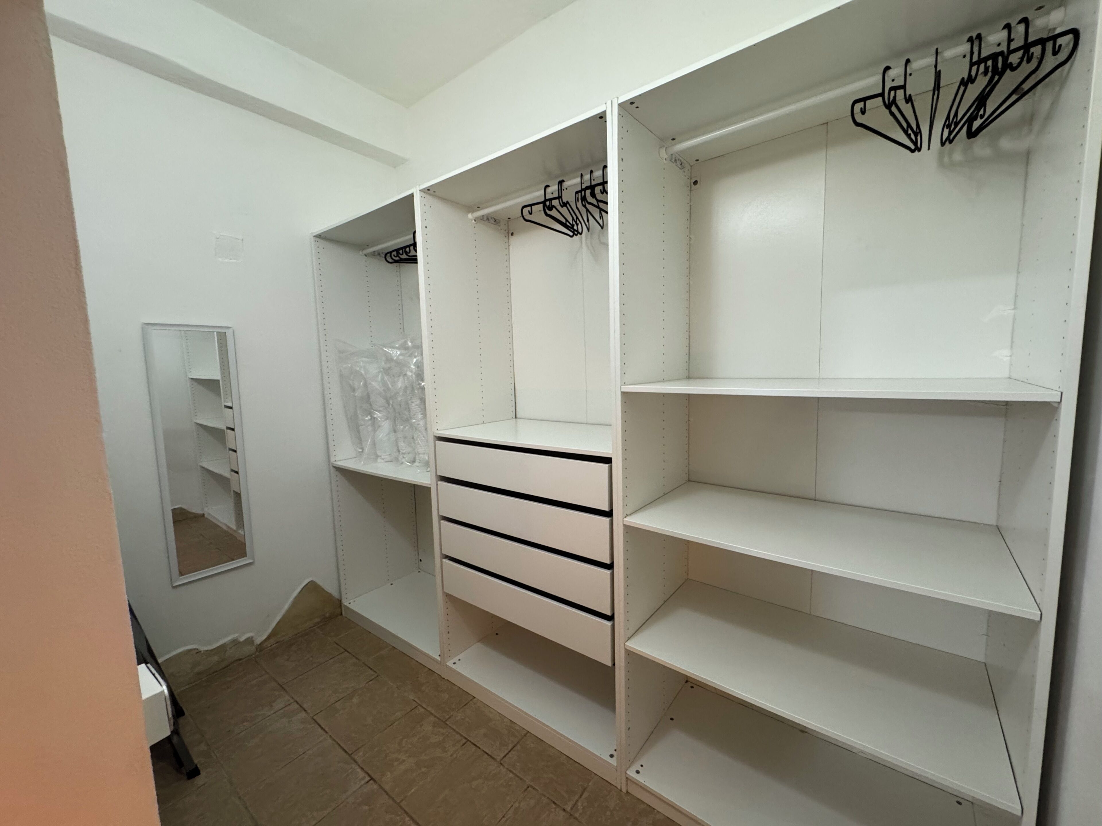 A walk-in closet with open shelves, a mirror, and hanging space.