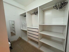 Ein begehbarer Kleiderschrank mit offenen Regalen, einem Spiegel und Kleiderstangen.