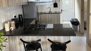 Uma cozinha moderna com uma ilha central, dois banquetas altas e uma janela.