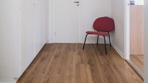 A room with a wooden floor, a white door, and a red chair.