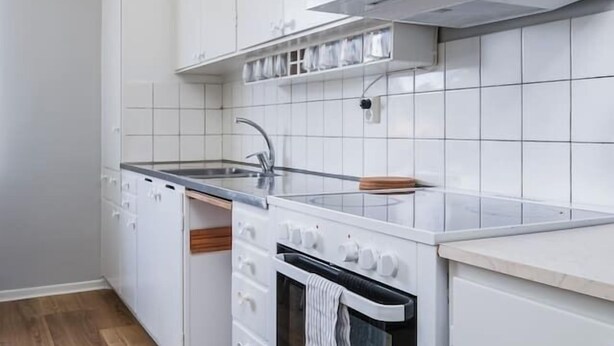 A kitchen with white cabinets, a stove, and a wooden floor.