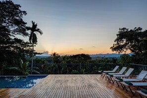 A wooden deck with a pool and lounge chairs facing a sunset. - Jalakara Havelock (Port Blair)