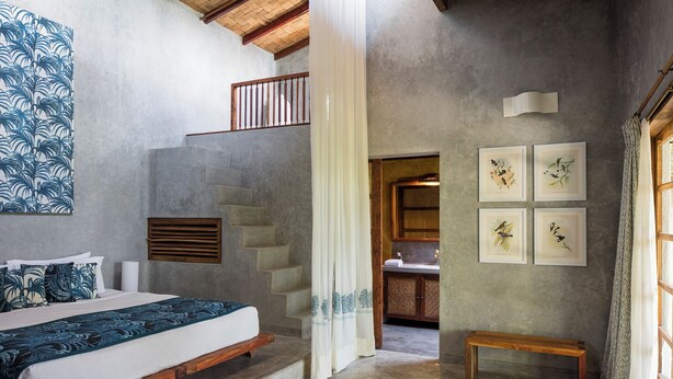 A bedroom with a bed, a bench, and a staircase.