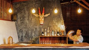 A bar area with a wooden counter, a decorative animal head, and bottles of liquor.