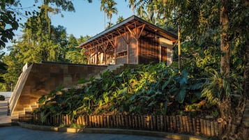A building with a wooden structure, surrounded by lush greenery and a stone staircase.
