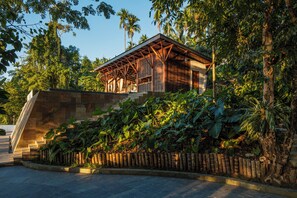 A building with a wooden structure, surrounded by lush greenery and a stone staircase.