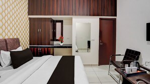 Ein Hotelzimmer mit einem Bett, einem Schreibtisch mit Kaffeemaschine, einem Sessel und einem Kleiderschrank.