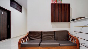 Ein Sofa aus Holz mit Lederkissen in einem Raum mit weißen Wänden und einem Fliesenboden.
