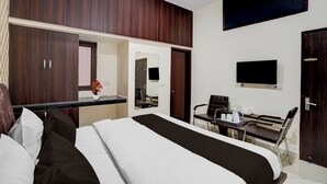 Ein Hotelzimmer mit Bett, Schreibtisch, Stuhl, Fernseher und Spiegel.