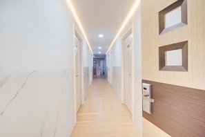 A corridor with doors on both sides, a wooden door with a keyhole, and a ceiling with recessed lighting. - Luxury Deluxe DBL Retreat W/ Free WiFi and Parking (Jakarta)