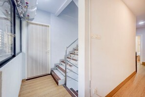 A staircase with a handrail leading to a landing, a door with a window, and a light switch on the wall. - Luxury Deluxe DBL Retreat W/ Free WiFi and Parking (Jakarta)