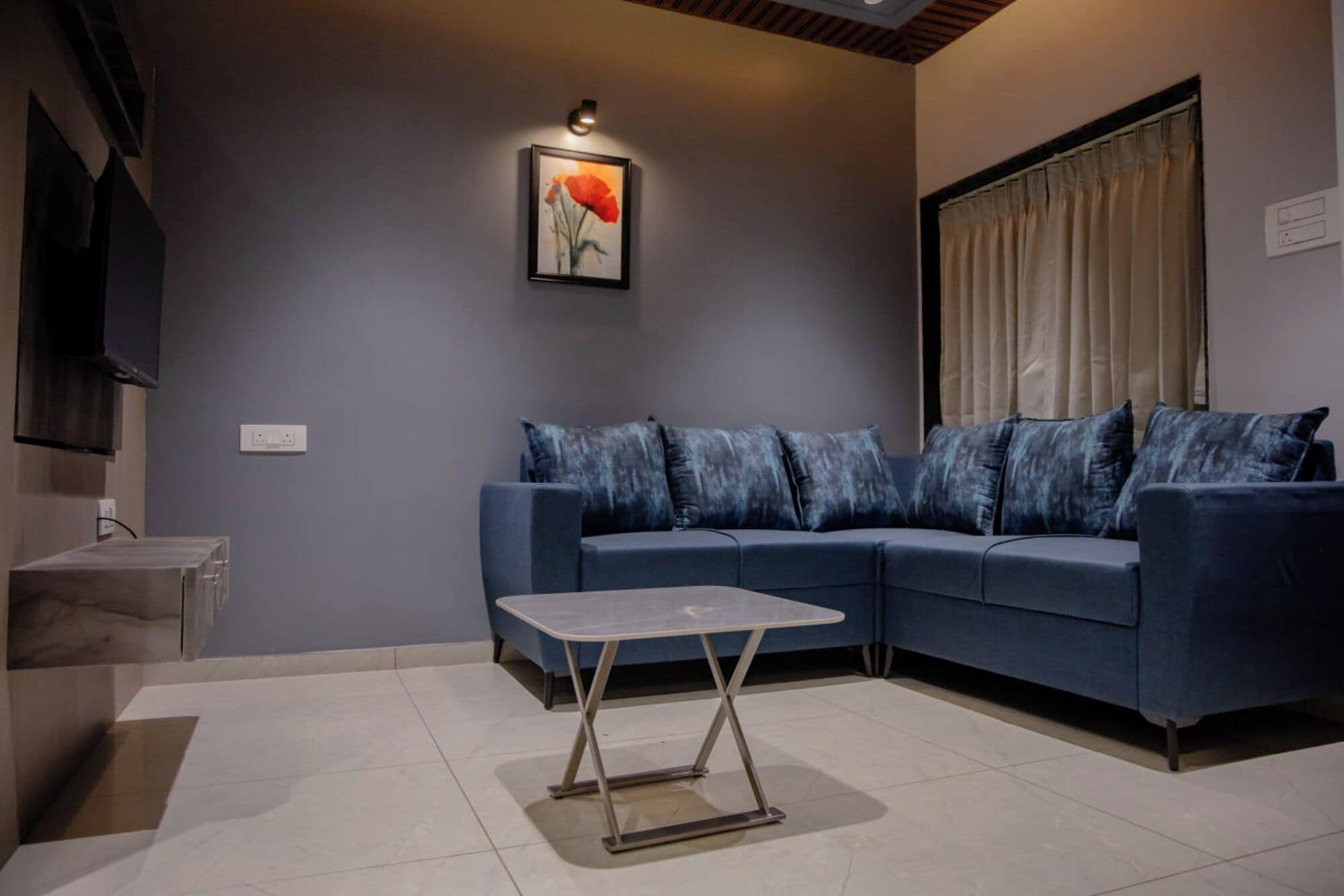 Un salon moderne avec un canapé bleu, une petite table et un tableau accroché au mur.