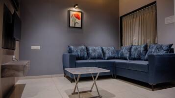 Un salon moderne avec un canapé bleu, une petite table et un tableau accroché au mur.