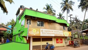 A two-story building with a green facade and a sign for 'Shree Siddhivinayak Enterprises.' - Kamath Homestay (Mavalli)