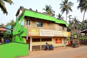 A two-story building with a green facade and a sign for 'Shree Siddhivinayak Enterprises.' - Kamath Homestay (Mavalli)