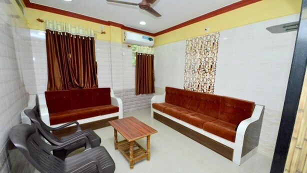 A room with two sofas, a wooden coffee table, and a ceiling fan. - Kamath Homestay (Mavalli)