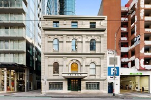 A historic building with a classic facade, a prominent entrance, and a parking sign indicating a parking facility nearby. - Spacious 3-Bed Apartment in Melbourne CBD (Melbourne)