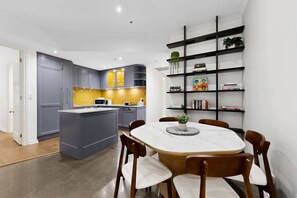 A modern kitchen with grey cabinets, a yellow backsplash, and a central island. - Spacious 3-Bed Apartment in Melbourne CBD (Melbourne)