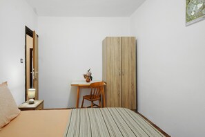 A bedroom with a bed, a desk with a chair, a wardrobe, and a lamp. - Apartment 'Volarić Pag' with Sea View, Balcony and Air Conditioning (Pag)