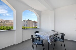 A balcony with a table and chairs, a view of a building, and a clear sky. - Apartment 'Volarić Pag' with Sea View, Balcony and Air Conditioning (Pag)