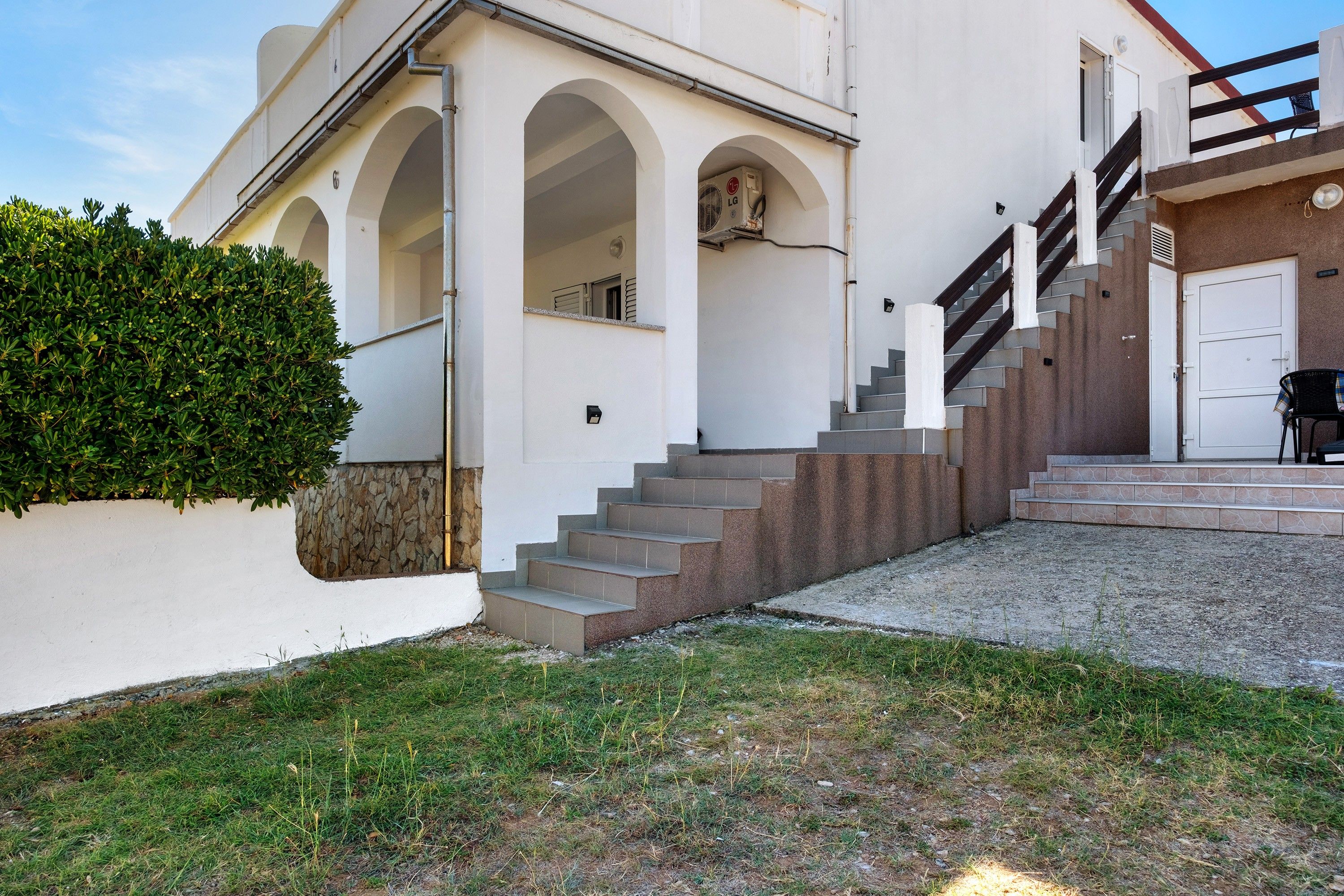 A modern building with a stone facade, a set of outdoor stairs, and a small garden area.