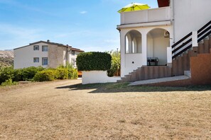 A two-story building with a stone facade, a covered outdoor seating area, and a staircase leading to the upper level. - Apartment 'Volarić Pag' with Sea View, Balcony and Air Conditioning (Pag)