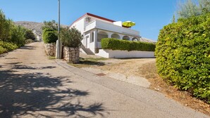 A building with a white facade, arched windows, and a red roof. - Apartment 'Volarić Pag' with Sea View, Balcony and Air Conditioning (Pag)