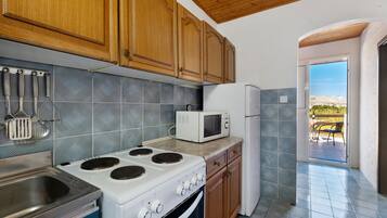 A kitchen with wooden cabinets, a stove, a microwave, and a refrigerator.