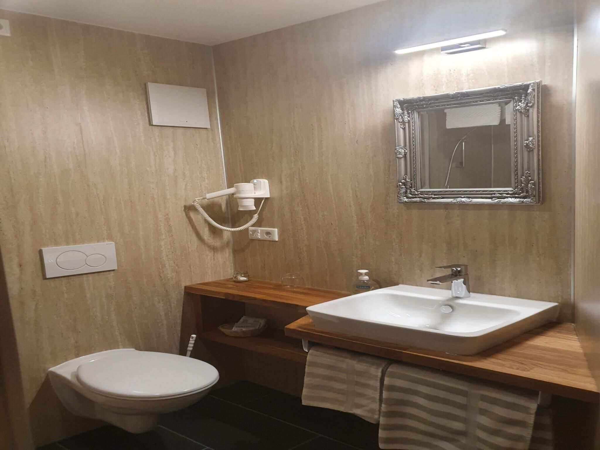 Un baño con inodoro, lavabo, espejo y toallero.