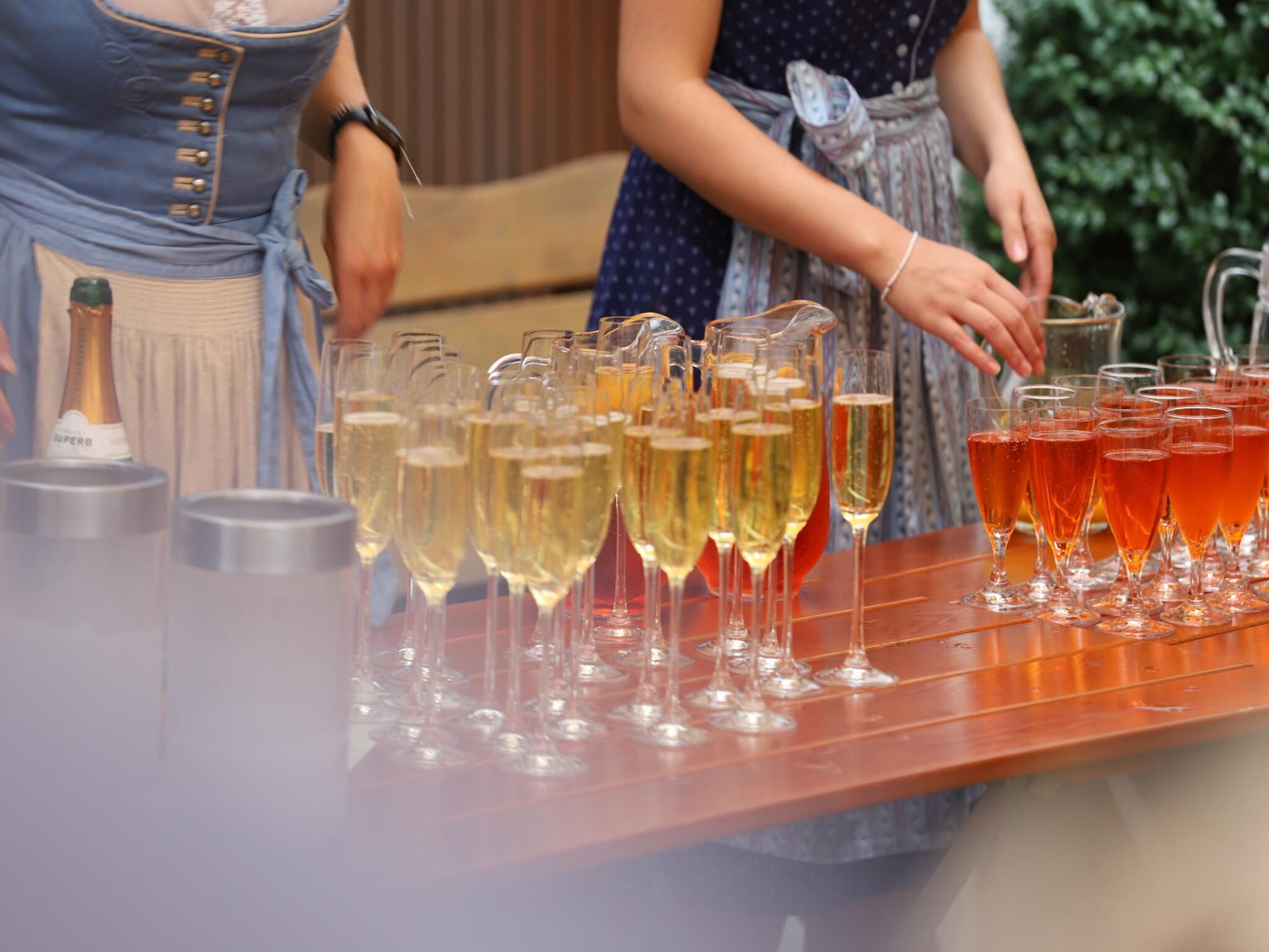 A bar area with multiple glasses of beverages, a bottle, and a pitcher.