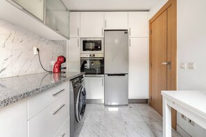 Eine kleine Küche mit Waschmaschine, Mikrowelle und Kühlschrank.